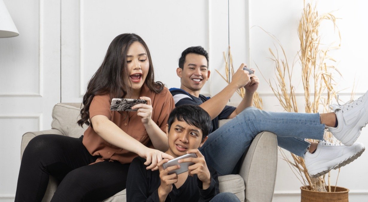 Friends laughing while playing a guessing game with ChatGPT on a smartphone