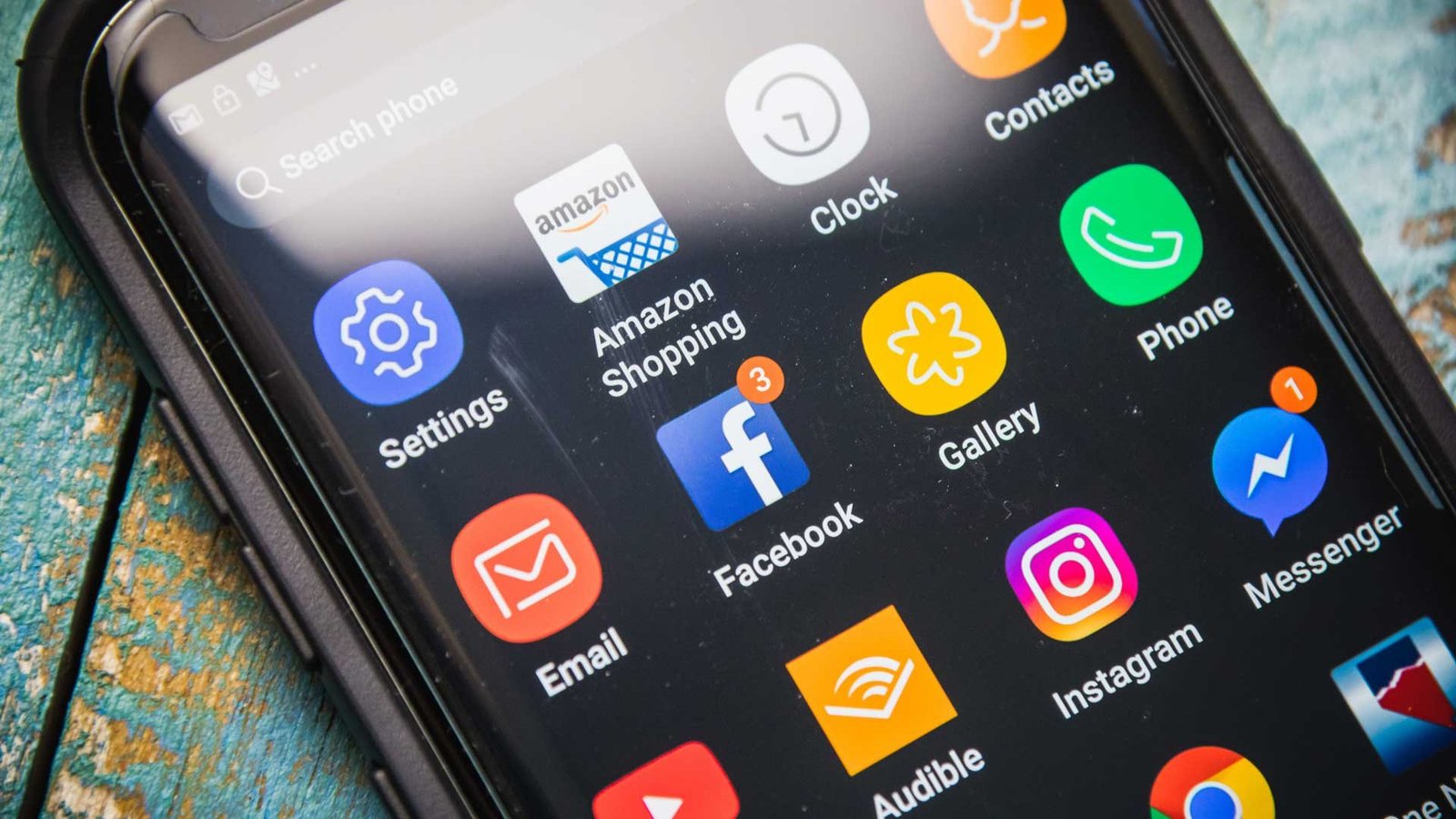 Hand holding an Android phone showing installed applications