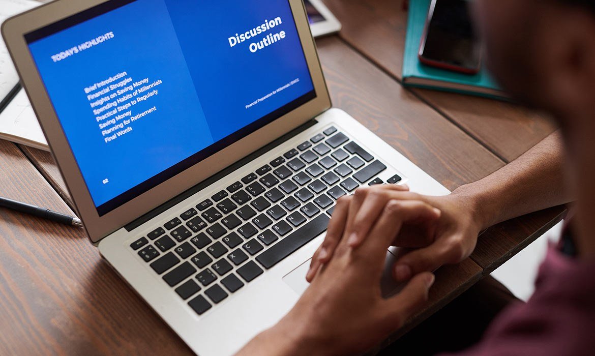 Person preparing presentation slides on a laptop at a desk