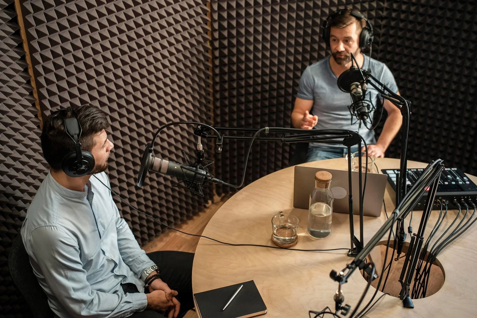 Podcast hosts recording in a professional studio with microphones